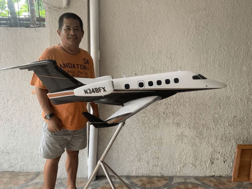 Noel Pineda, founder of Wingcraft Models, holding a finished Embraer Phenom 300 scale model in the family workshop