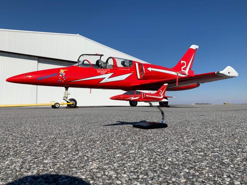 Red and white jet trainer scale model handmade by Wingcraft Models, photographed on an airfield