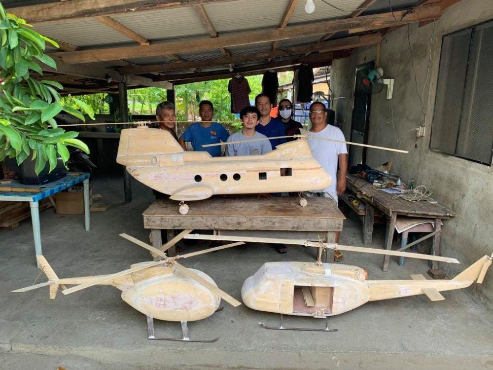 The Wingcraft Models family workshop crew with three large helicopter models being shaped by hand